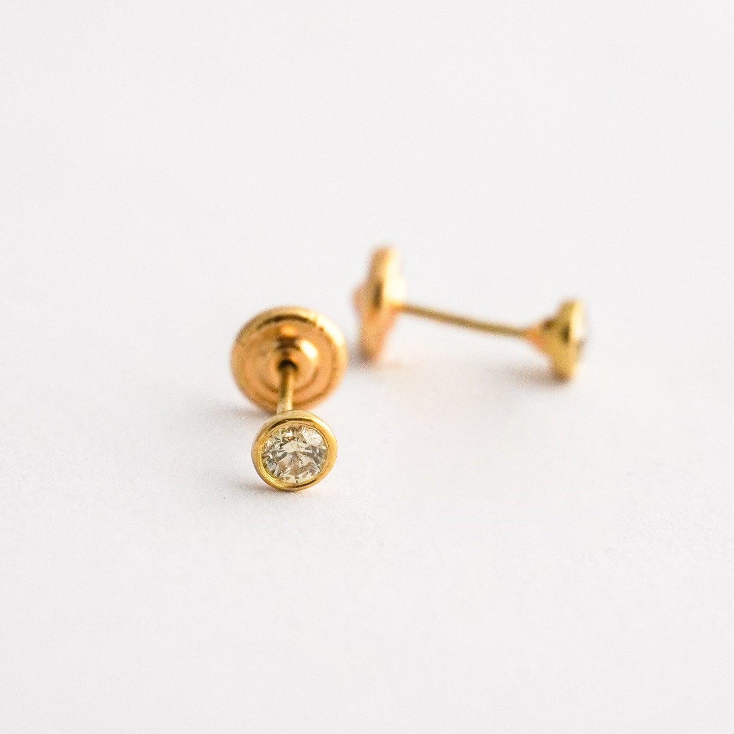 Aretes bebé punto de luz bicelado con diamante natural en oro 18k