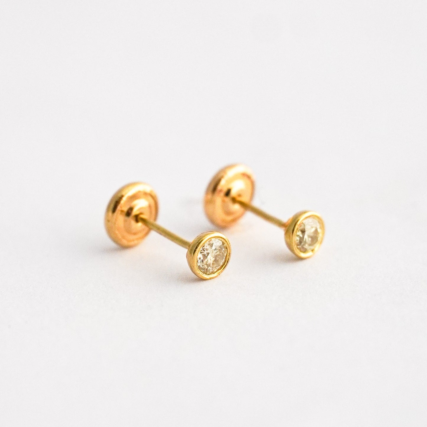 Aretes bebé punto de luz bicelado con diamante natural en oro 18k